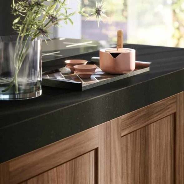 a black counter top with a vase of flowers and a teapot on it